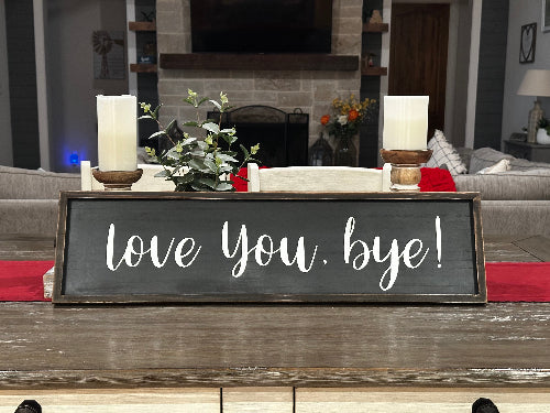 Decorative sign with 'love You, bye!' text in a living room setting.