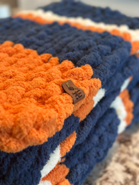 Close-up of a blue and orange knitted blanket with a leather tag.
