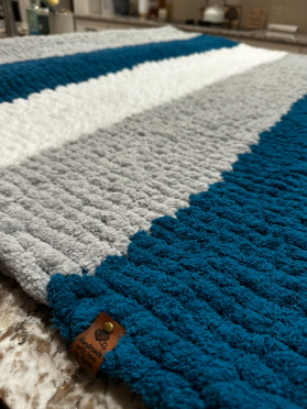 Textured blue and gray blanket on a surface with a visible brand tag.