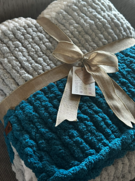 Knitted blue blanket with a bow on a textured surface